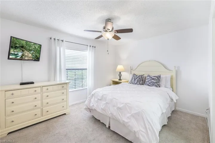 Bedroom with a textured ceiling, light colored carpet, and ceiling fan
