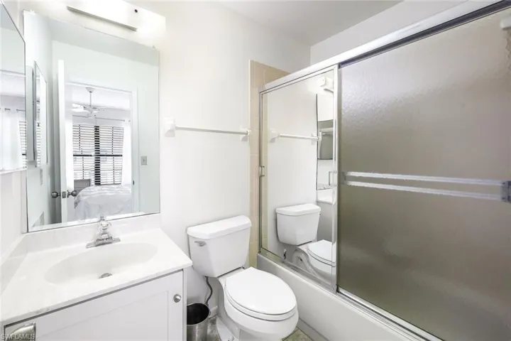 Full bathroom featuring shower / bath combination with glass door, vanity, ceiling fan, and toilet