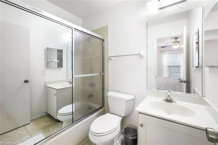 Full bathroom with vanity, combined bath / shower with glass door, ceiling fan, and toilet