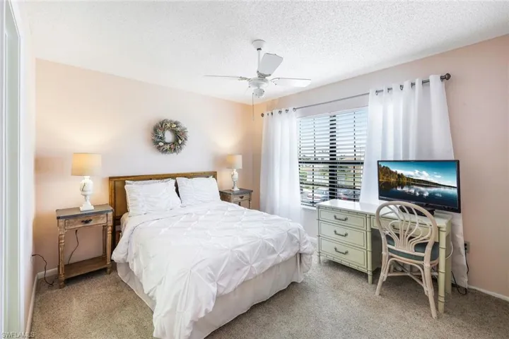 Bedroom featuring light carpet, ceiling fan, and a textured ceiling