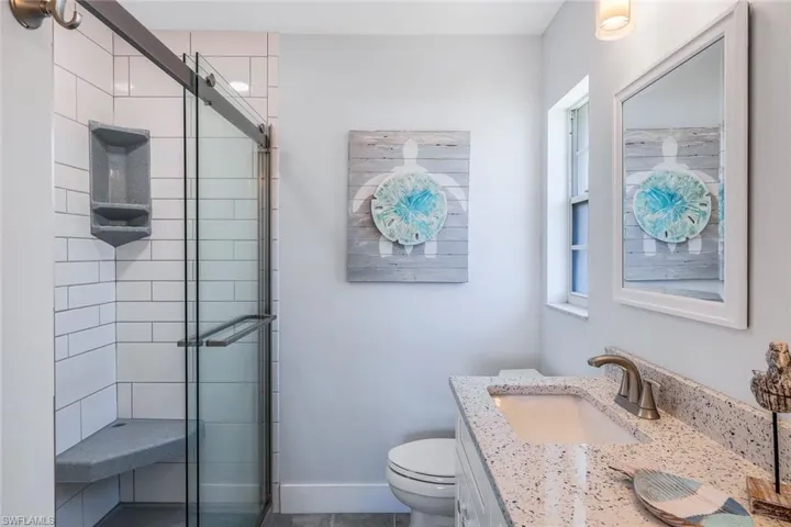 Bathroom with vanity, a shower with shower door, toilet, and tile patterned floors