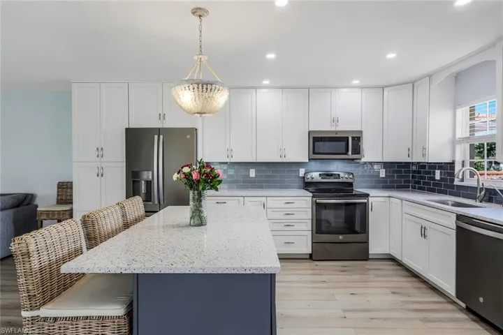 Kitchen with decorative light fixtures, decorative backsplash, sink, appliances with stainless steel finishes, and light hardwood / wood-style flooring