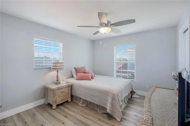 Bedroom featuring multiple windows, ceiling fan, and light wood-type flooring