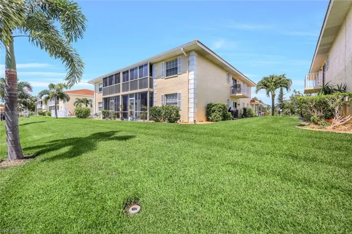 Rear view of property with a balcony and a lawn
