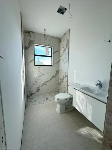 Bathroom featuring vanity and a marble finish shower