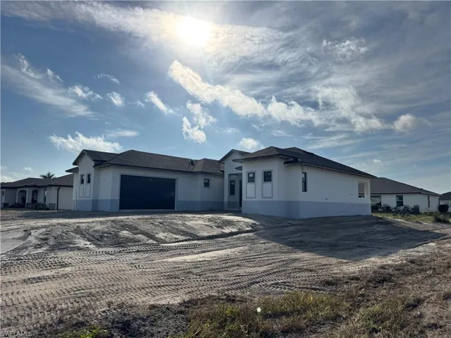 View of front facade with stucco siding, driveway, and an attached garage