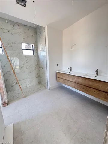Bathroom featuring a marble finish shower and double vanity