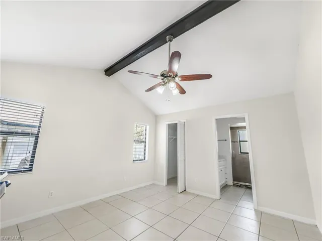 Unfurnished bedroom featuring light tile patterned floors, a closet, baseboards, and a spacious closet