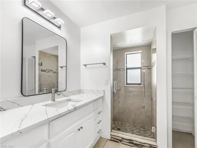 Full bathroom with vanity, tile patterned floors, a shower stall, and a walk in closet