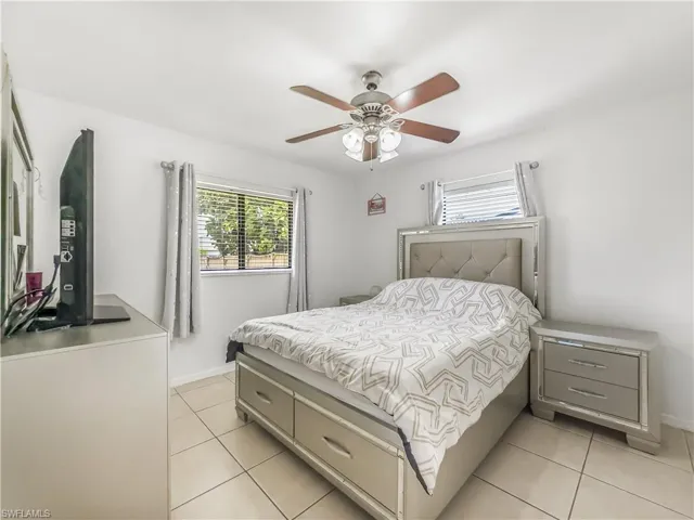 Bedroom with light tile patterned floors, baseboards, and ceiling fan