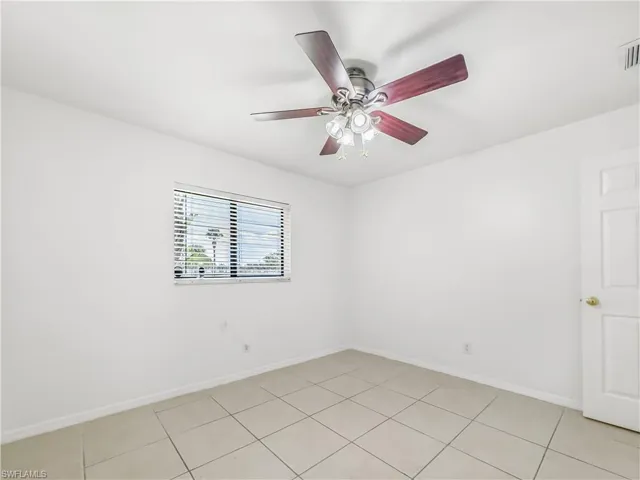 Empty room featuring baseboards, light tile patterned flooring, and a ceiling fan