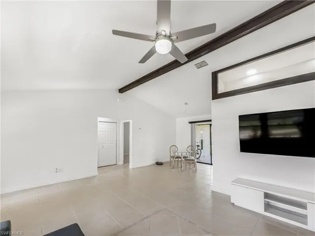 Unfurnished living room featuring ceiling fan, tile patterned flooring, and baseboards