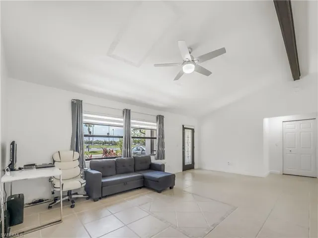 Living room with lofted ceiling, a ceiling fan, and light tile patterned flooring