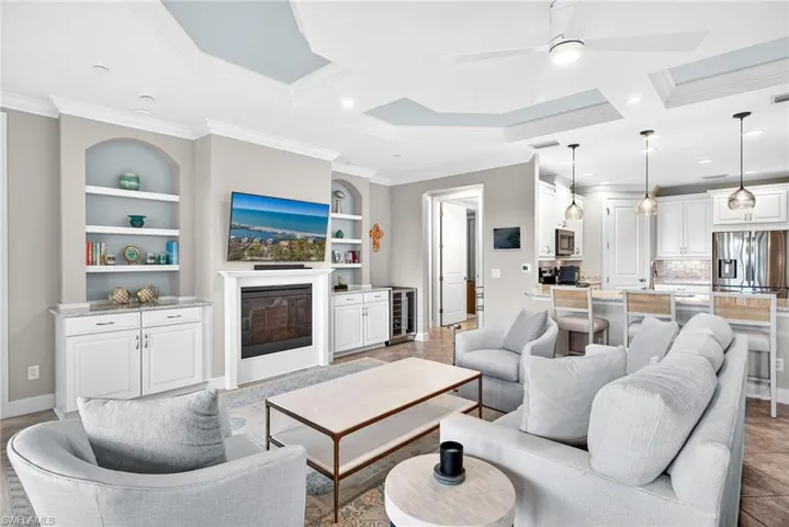 Living room with a glass covered fireplace, built in features, wine cooler, ceiling fan, and recessed lighting