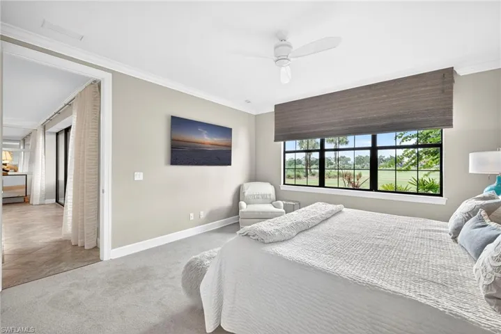 Carpeted bedroom featuring ornamental molding, a ceiling fan, and tile patterned floors