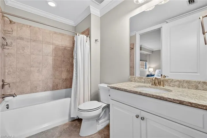 Bathroom featuring shower / tub combo with curtain, crown molding, vanity, and light tile patterned flooring