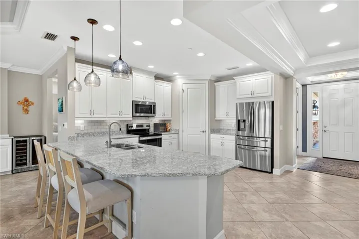 Kitchen with crown molding, appliances with stainless steel finishes, a peninsula, recessed lighting, and tasteful backsplash