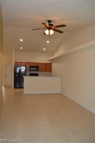 Kitchen with wood finish cabinets, vaulted ceiling, ceiling fan, recessed lighting, and black appliances