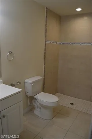 Bathroom with vanity, a tile shower, recessed lighting, and light tile patterned floors