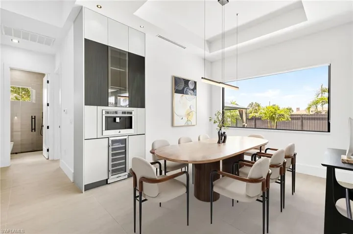 Dining room featuring wine cooler, a tray ceiling, and recessed lighting