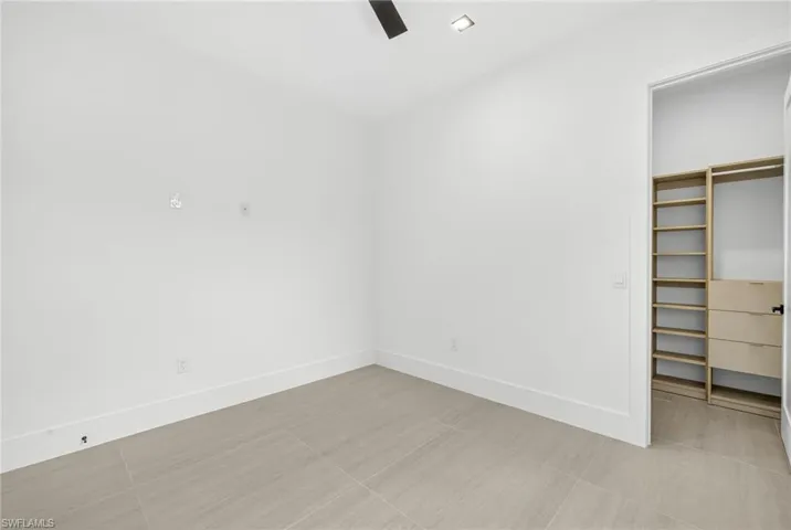Unfurnished bedroom with a ceiling fan, a walk in closet, and light tile patterned flooring