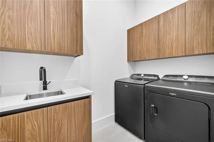 Washroom featuring cabinet space, washing machine and dryer, and light tile patterned flooring