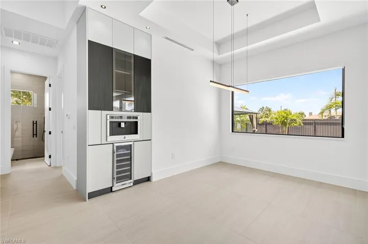 Kitchen with wine cooler, modern cabinets, white cabinets, a raised ceiling, and recessed lighting