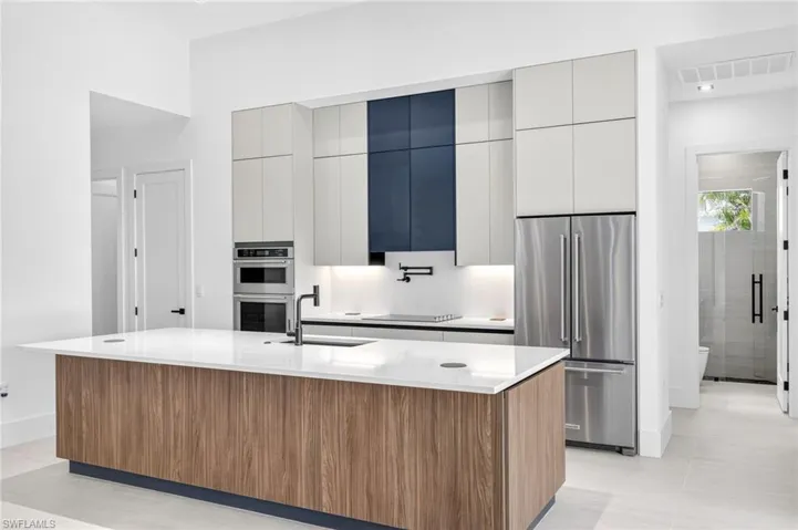 Kitchen with stainless steel appliances, modern cabinets, a large island, and light countertops