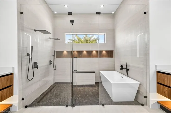 Bathroom with a soaking tub, a stall shower, vanity, and tile walls