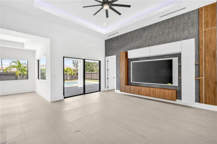 Unfurnished living room with an accent wall, a raised ceiling, and ceiling fan