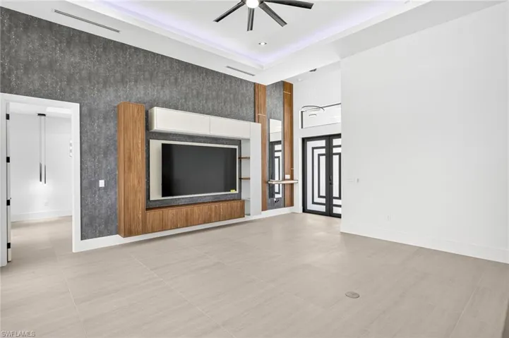Unfurnished living room with a ceiling fan, a towering ceiling, recessed lighting, and tile patterned flooring