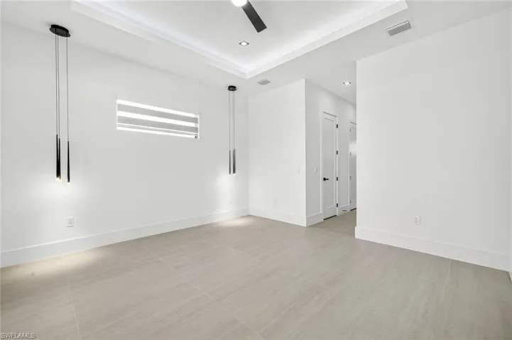 Spare room with a raised ceiling, ceiling fan, recessed lighting, and light tile patterned flooring