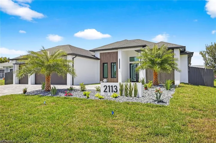 Prairie-style home featuring an attached garage, decorative driveway, and stucco siding