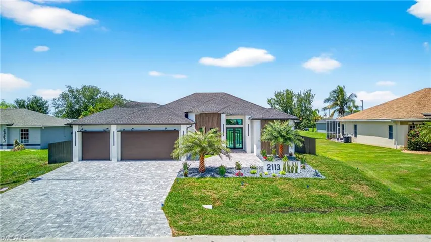 View of front facade with an attached garage, a front lawn, decorative driveway, and stucco siding