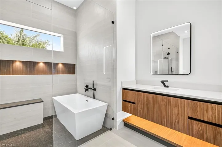 Bathroom with tile walls, a soaking tub, vanity, a shower, and tile patterned floors