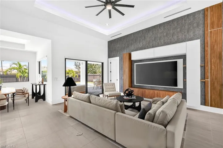 Living room featuring an accent wall, a raised ceiling, ceiling fan, and a towering ceiling