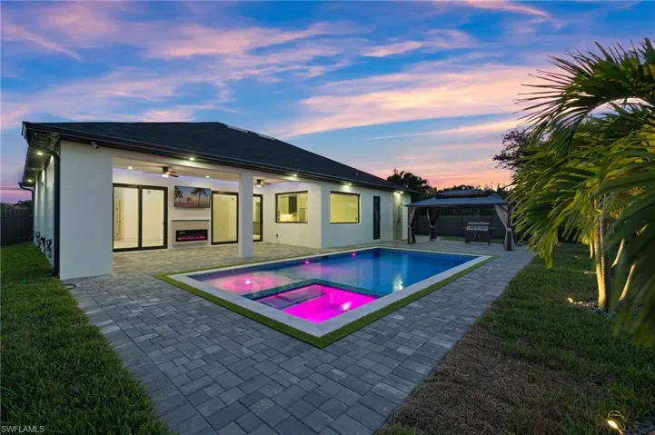 Rear view of house featuring a gazebo, a patio area, a fenced backyard, stucco siding, and a pool with connected hot tub