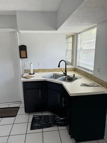 Kitchen with sink, a textured ceiling, and light tile floors