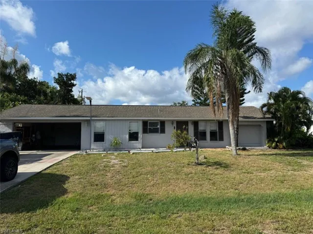 Ranch-style house with a garage and a front lawn