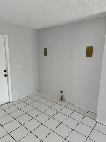 Washroom with a textured ceiling and light tile floors