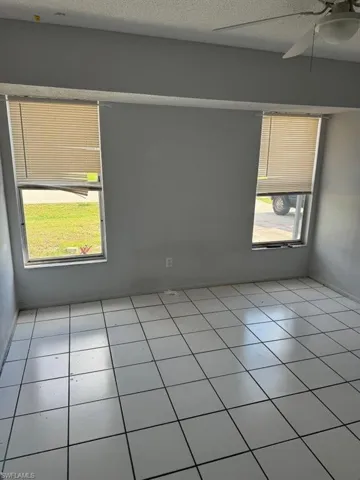 Spare room with a textured ceiling, ceiling fan, and light tile flooring