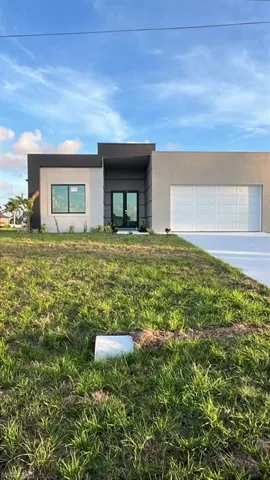 Contemporary exterior with a two-tone facade, prominent entry with double doors, attached garage, and a concrete driveway