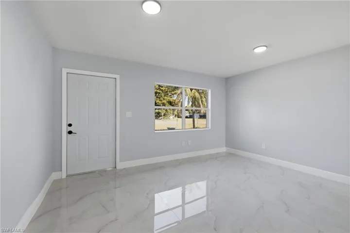 Spare room featuring light marble finish flooring and baseboards