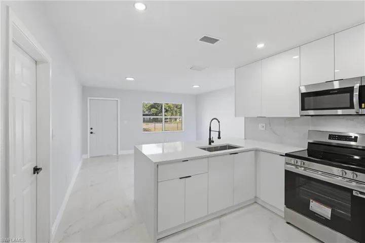 Kitchen with appliances with stainless steel finishes, modern cabinets, white cabinets, and recessed lighting