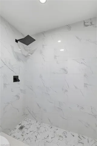 Full bathroom featuring a marble finish shower and toilet