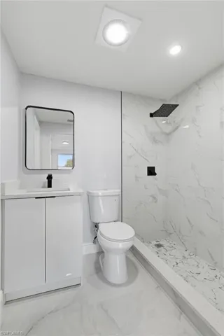 Full bathroom with vanity, a marble finish shower, recessed lighting, and light marble finish floors