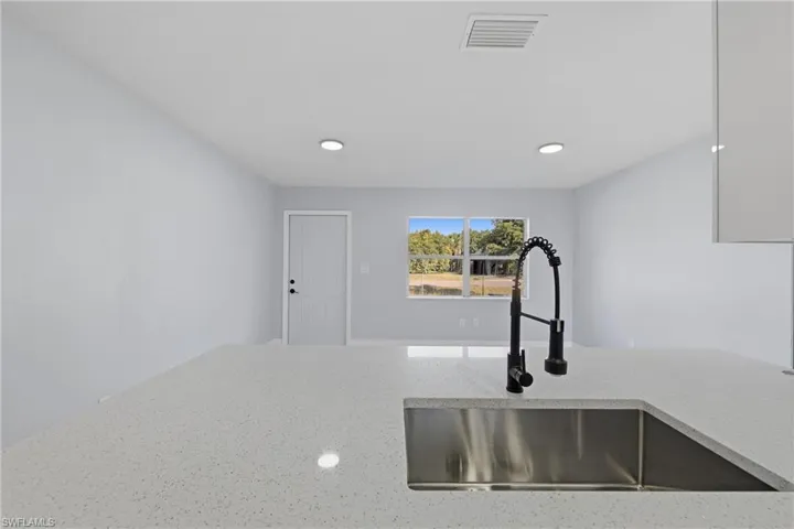 Kitchen view of light stone countertops and recessed lighting