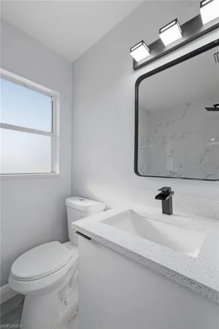 Bathroom featuring vanity, marble look tile flooring, and a marble finish shower