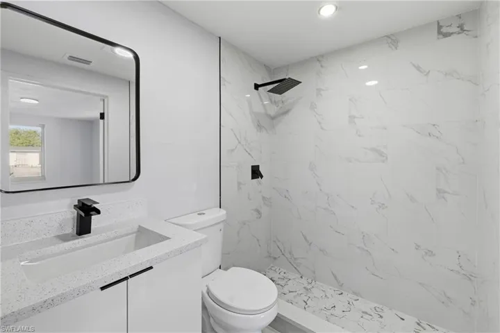 Bathroom featuring vanity, a marble finish shower, and recessed lighting
