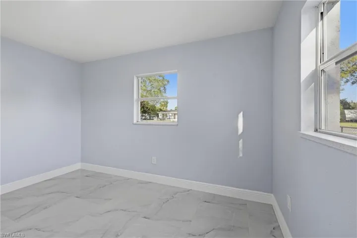Empty room featuring light marble finish flooring and baseboards
